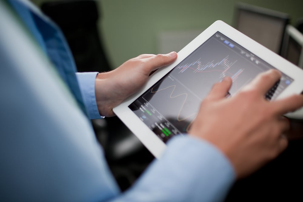 An employee performs market research and looks at a graph on a tablet.