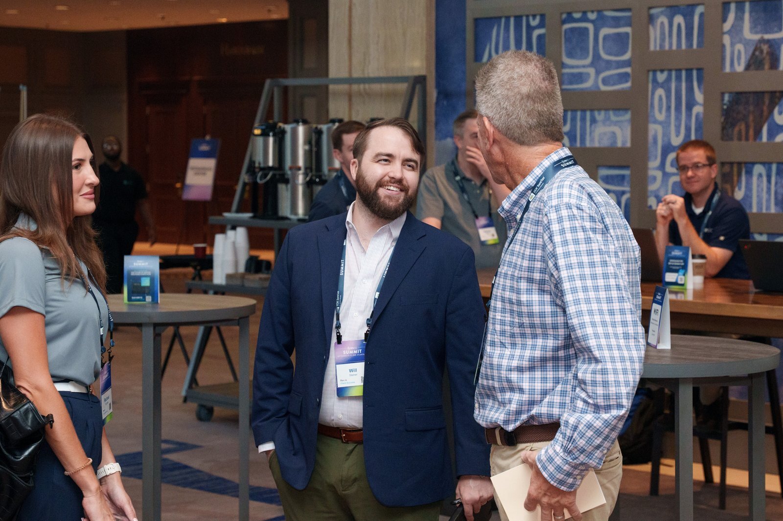 Three Summit attendees in business attire chatting between sessions in the expo hall